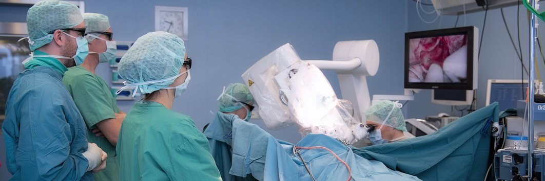 Operation wird von drei Mediziner:innen am Monitor verfolgt