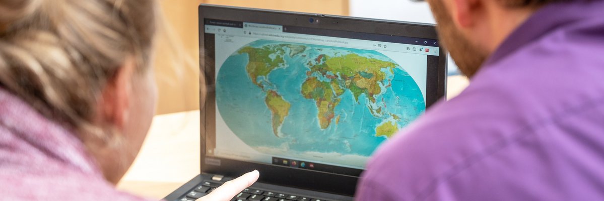 Zwei Menschen schauen sich eine Weltkarte auf dem Laptop an
