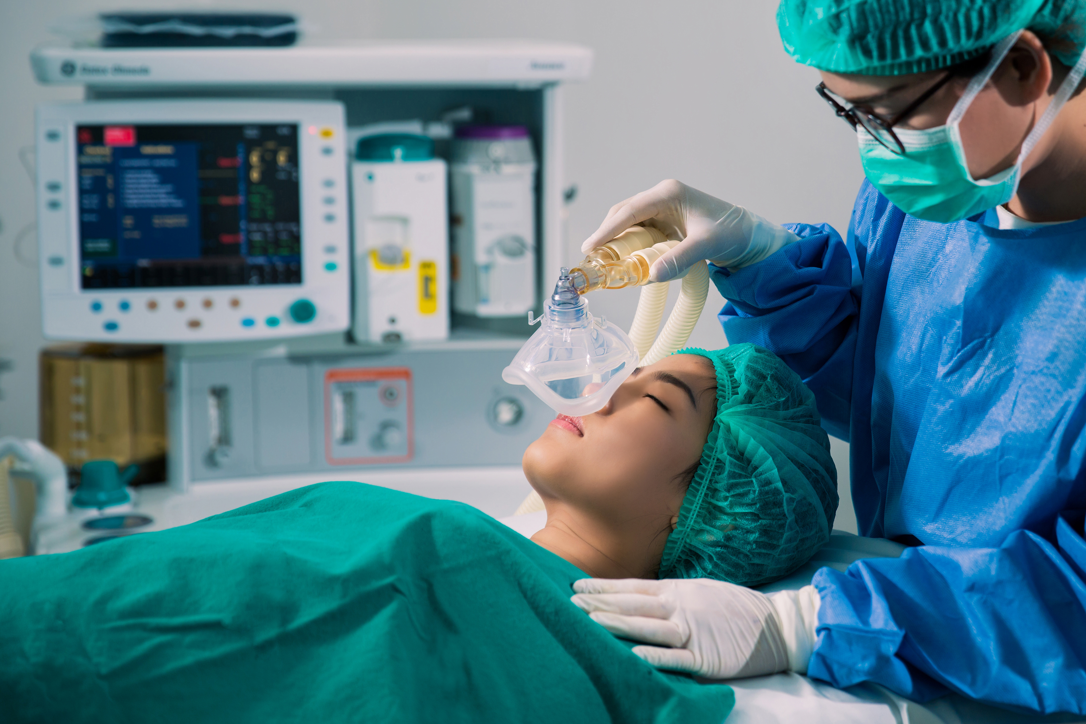 Medizinisches Personal legt ein Beatmungsgerät bei einer liegenden Patientin im Behandlungsraum an