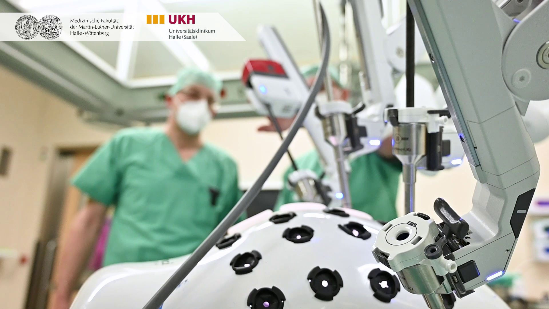 Im Vordergrund ist der Da-Vinci-OP-Roboter zu sehen, im Hintergrund medizinische Mitarbeitende in grüner Arbeitskleidung