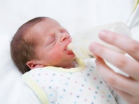 Baby bekommt Milch in einem Fläschchen