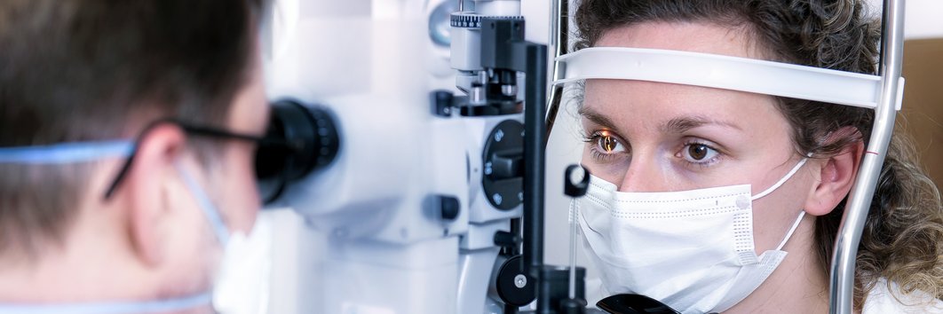 Ein Arzt untersucht mit einem speziellem Gerät die Augen einer Patientin