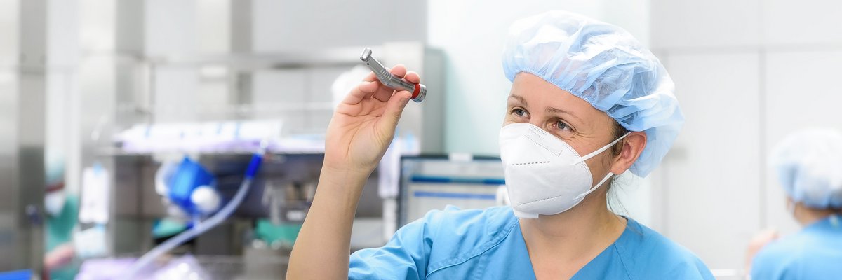 Frau in steriler Kleidung überprüft zahnärztliches Gerät 
