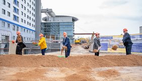 Fünf Menschen beim Spatenstich für neues Gebäude der Universitätsmedizin Halle (Saale). Im Hintergrund ist das Hauptgebäude des Universitätsklinikum zu sehen.