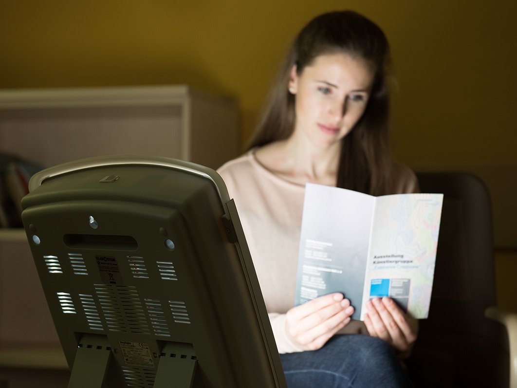 Frau lesend vor Lichttherapielampe