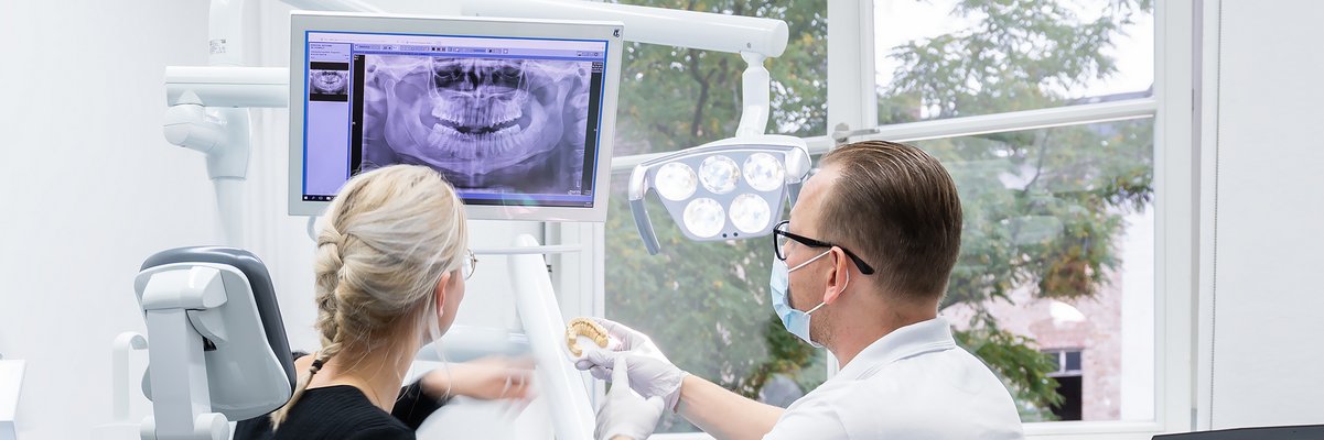 Zahnarzt und Patientin schauen auf ein Röntgenbild