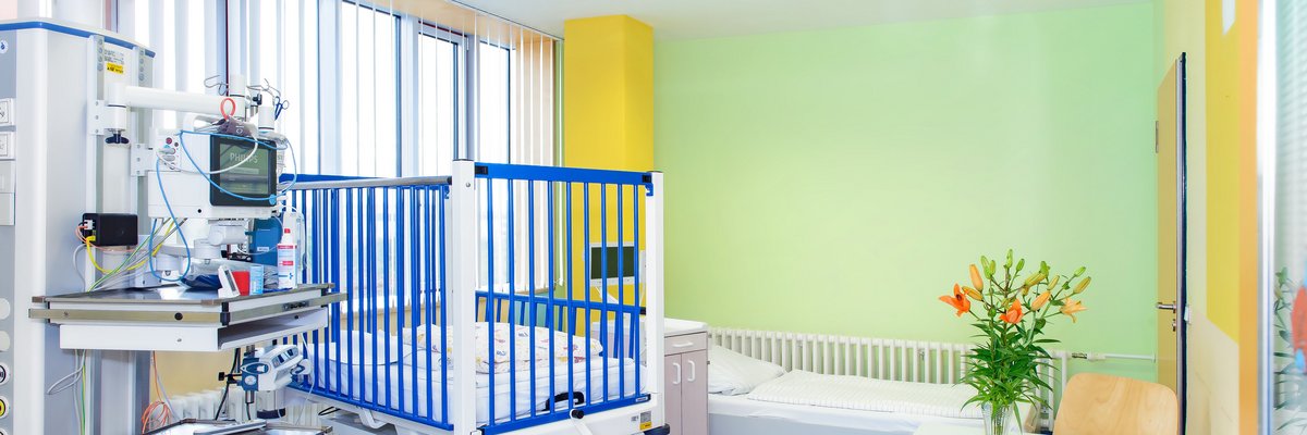 Patientenzimmer für Eltern und Kind. Gitterbett und normales Bett, ein Tisch