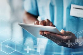 Symbolbild für digitale Medizin: Ein medizinischer Mitarbeiter hält ein Tablet in den Händen, daneben grafische Elemente, die das Thema Krankenhaus illustrieren.