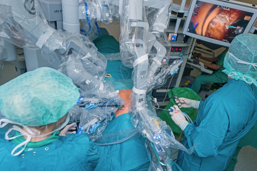 OP-Roboter und Operateure in grüner Schutzkleidung während einer Operation.  OP-Roboter und Operateure in grüner Schutzkleidung während einer Operation.